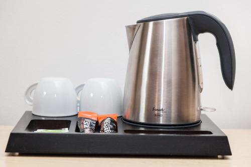 a tea kettle and two cups on a counter at Penzion Pohoda in Trutnov