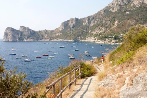 a path leading down to a body of water with boats at Taverna Del Capitano in Massa Lubrense