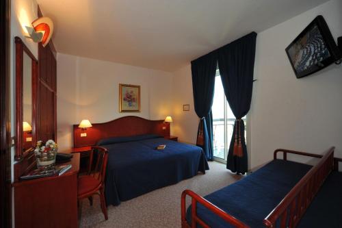 ein Hotelzimmer mit Bett, Schreibtisch und Fenster in der Unterkunft Hotel Beny in Lido di Jesolo