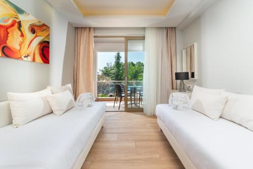 ネオス・マルマラスにあるPoseidon Hotel Sea Resortのバルコニー付きの客室で、白いベッド2台が備わります。