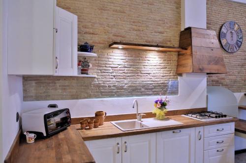 una cocina con fregadero y un reloj en una pared de ladrillo en Casa Francesca Torre Saracena, en Dolcedo