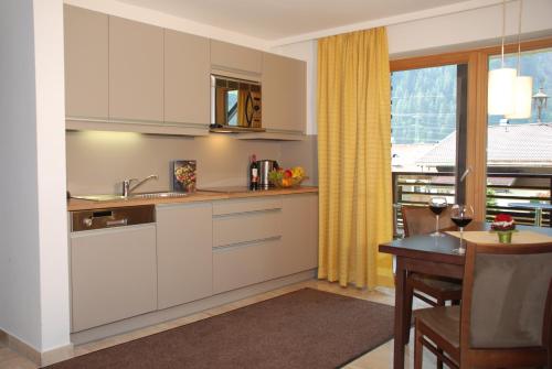 cocina con armarios blancos, mesa y ventana en Apart-Garni Innerwiesn, en Mayrhofen