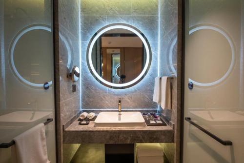 a bathroom with a sink and a mirror at Mercure Shanghai Jiuting in Shang-hai