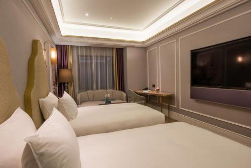 a hotel room with two beds and a flat screen tv at Mercure Shanghai Jiuting in Shang-hai