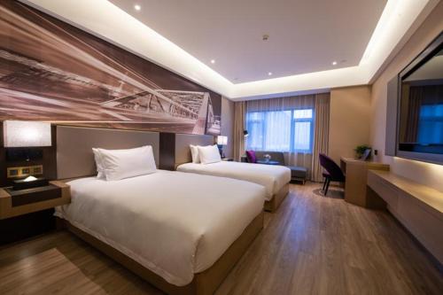 a hotel room with two beds and a flat screen tv at Mercure Shanghai Jiuting in Shang-hai