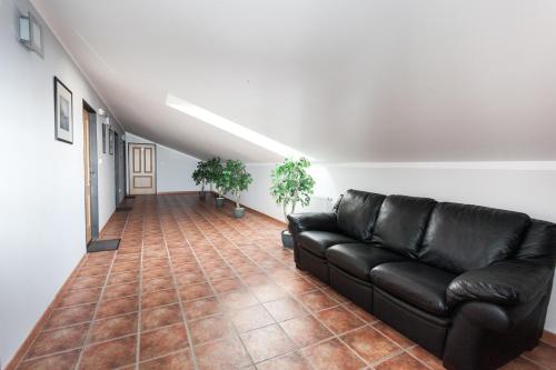 a living room with a black leather couch and plants at Penzion Pohoda in Trutnov