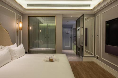 a bedroom with a white bed and a television at Mercure Shanghai Jiuting in Shang-hai