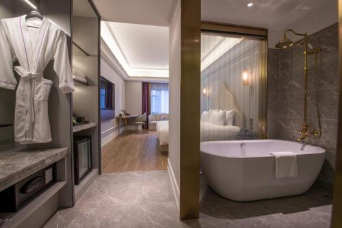 a bathroom with a bath tub and a bedroom at Mercure Shanghai Jiuting in Shang-hai