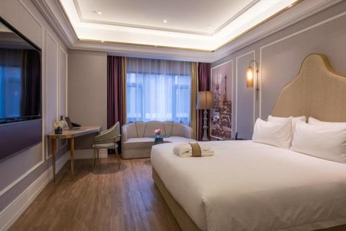 a hotel room with a large bed and a desk at Mercure Shanghai Jiuting in Shang-hai