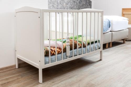 a white crib in a room with a bed at Penzion Pohoda in Trutnov