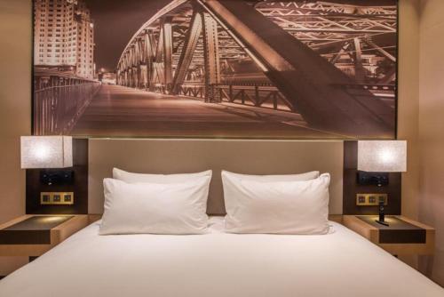 a large bed with a painting of a bridge at Mercure Shanghai Jiuting in Shang-hai