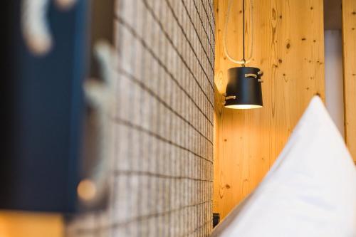a light hanging from a brick wall with a building at DAS VIER Sport,- und Wellnesshotel in Sankt Leonhard im Pitztal