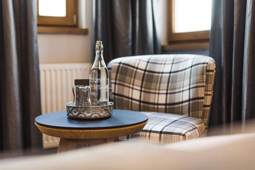 a bottle on a table next to a chair at DAS VIER Sport,- und Wellnesshotel in Sankt Leonhard im Pitztal