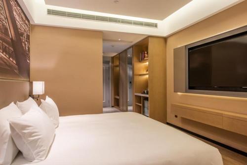 a bedroom with a bed with a flat screen tv at Mercure Shanghai Jiuting in Shang-hai