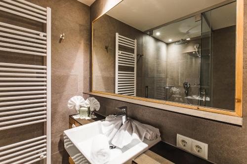 a bathroom with a sink and a mirror at DAS VIER Sport,- und Wellnesshotel in Sankt Leonhard im Pitztal