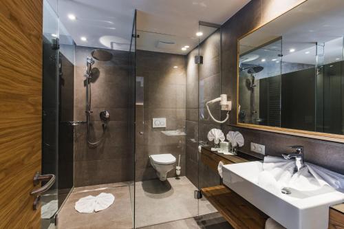 a bathroom with a sink and a shower and a toilet at DAS VIER Sport,- und Wellnesshotel in Sankt Leonhard im Pitztal