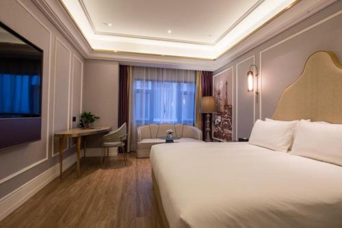 a hotel room with a large bed and a desk at Mercure Shanghai Jiuting in Shang-hai