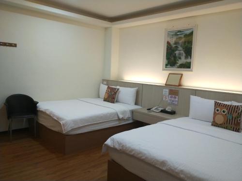a hotel room with two beds and a chair at Oriental Hotel in Taimali