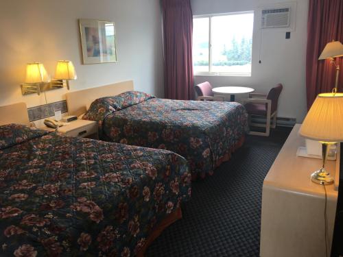 a hotel room with two beds and a table at DC Lodge in Dawson Creek