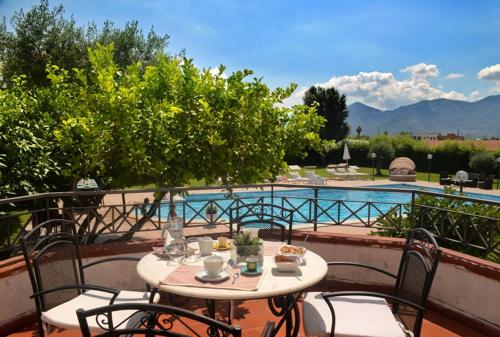 un tavolo e sedie su un balcone accanto alla piscina di Pompeii Garden House a Scafati