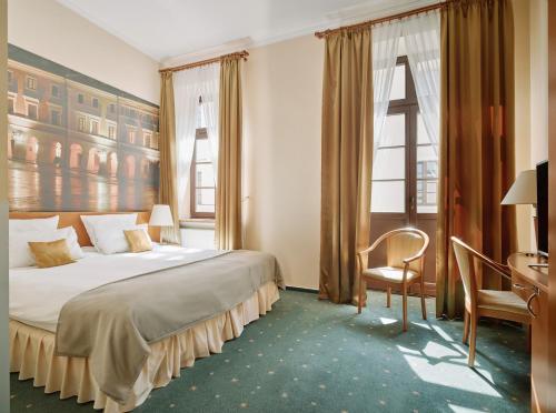 a hotel room with a bed and a desk and window at Hotel Zamojski in Zamość