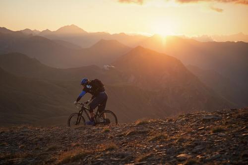 a man riding a bike on a hill at sunset at Superior Hotel Post Ischgl in Ischgl