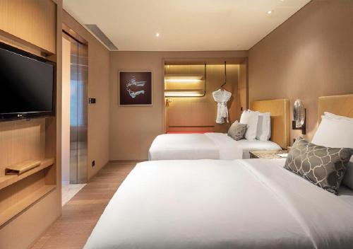 a hotel room with two beds and a flat screen tv at Grand Bay Hotel Zhuhai in Zhuhai