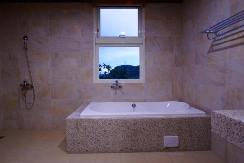 a large bath tub in a bathroom with a window at DooDoo B&B in Jiji