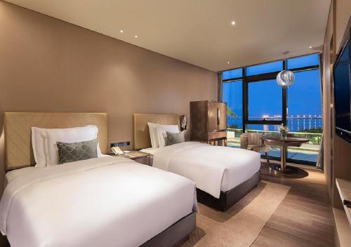 a hotel room with two beds and a balcony at Grand Bay Hotel Zhuhai in Zhuhai