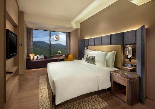 a bedroom with a large bed and a living room at Grand Bay Hotel Zhuhai in Zhuhai