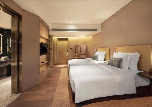 a hotel room with two beds and a television at Grand Bay Hotel Zhuhai in Zhuhai