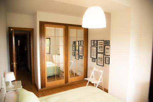 a room with a glass door with a chair and a bedroom at Casa de Las Flores - Apartamento con jardín privado frente a la Playa de Comillas in Comillas