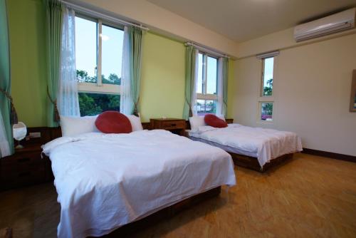 a bedroom with two beds and two windows at DooDoo B&B in Jiji