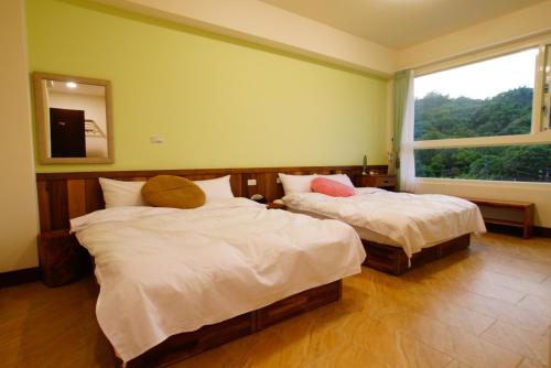 two beds in a room with a window at DooDoo B&B in Jiji