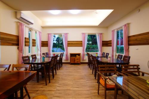 a dining room with tables and chairs and windows at DooDoo B&B in Jiji
