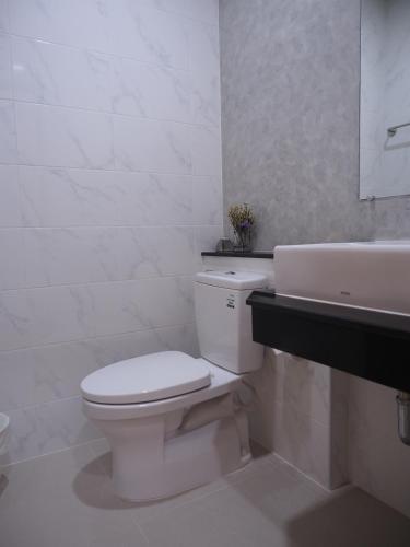 a white bathroom with a toilet and a sink at Luck Esan Loft in Ubon Ratchathani