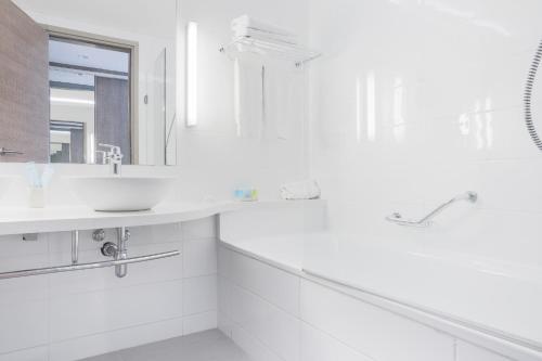 a bathroom with a sink, toilet and bathtub at Vassos Nissi Plage Hotel & Spa in Ayia Napa