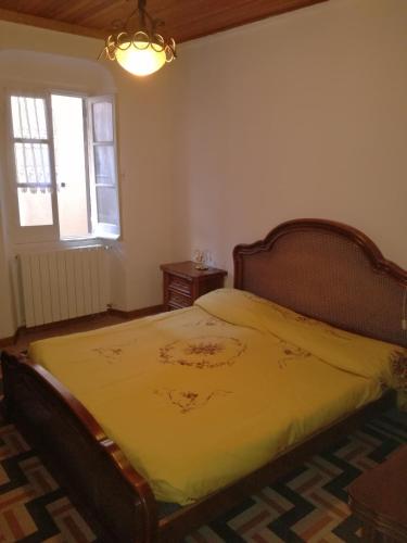 a bedroom with a bed with a yellow blanket at Appartamento nel centro storico di Sassello in Sassello