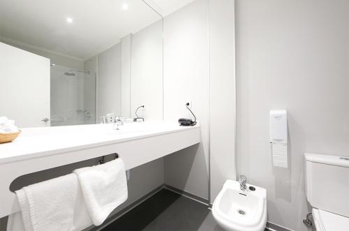 a white bathroom with a sink and a toilet at Hotel Loiola in Azpeitia