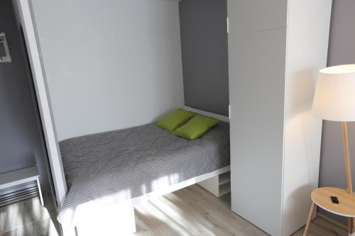 ein kleines Bett in einem kleinen Zimmer mit einem grünen Kissen in der Unterkunft Modern & Homely Apartment - FREE PARKING - NETFLIX in Kaunas
