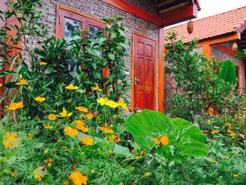 a garden with yellow flowers in front of a house at Tam Coc Friendly Homestay in Ninh Binh