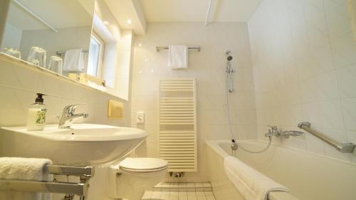 施利爾塞的住宿－施利爾斯伯格阿爾姆酒店，浴室配有盥洗盆、卫生间和浴缸。
