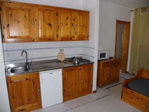 a kitchen with wooden cabinets and a sink at Residence Buganvillea in Alghero