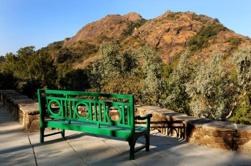 a green bench sitting in front of a mountain at Palace Hotel - Bikaner House in Mount Ābu
