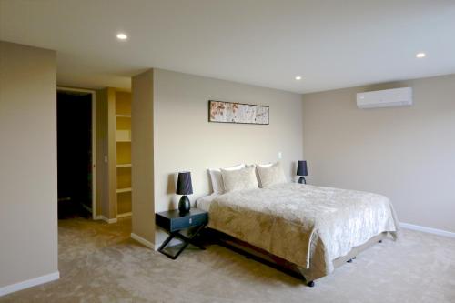 a bedroom with a bed and a lamp on a table at Golden Sun Apartment -Two bedrooms, Three bedrooms in Christchurch