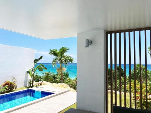 a door to a villa with a view of the ocean at Feliz Villa Suite Miyakojima Ueno in Miyako Island