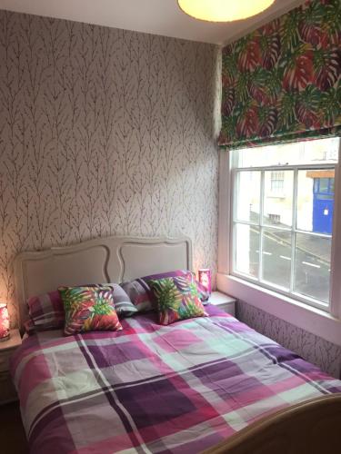 a bedroom with a bed with a plaid blanket and a window at Central city pad one bedroom plus double sofabed in Bath