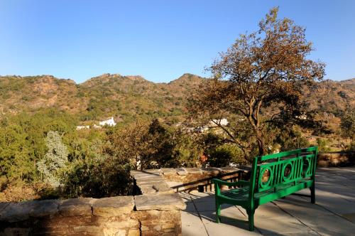 a green bench sitting next to a stone wall at Palace Hotel - Bikaner House in Mount Ābu