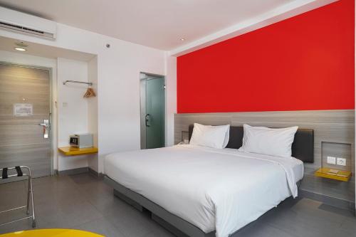 1 dormitorio con 1 cama grande y pared roja en Amaris Hotel Sriwedari Solo, en Solo