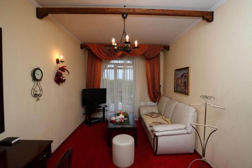 a living room with a white couch and a tv at Medzhybozhskiy Zamok in Tribukhovtsy